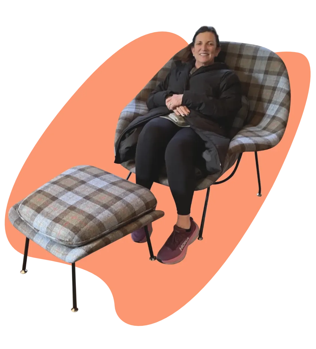 Happy woman seated in her newly restored tartan fabric Knoll Studio Womb Lounge Chair